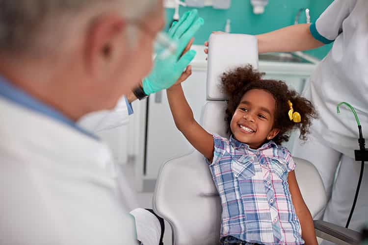 A child smiling and giving her dentist a high-five!